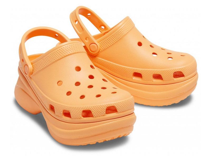 Пара оранжевых Crocs Bae Clog на белом фоне